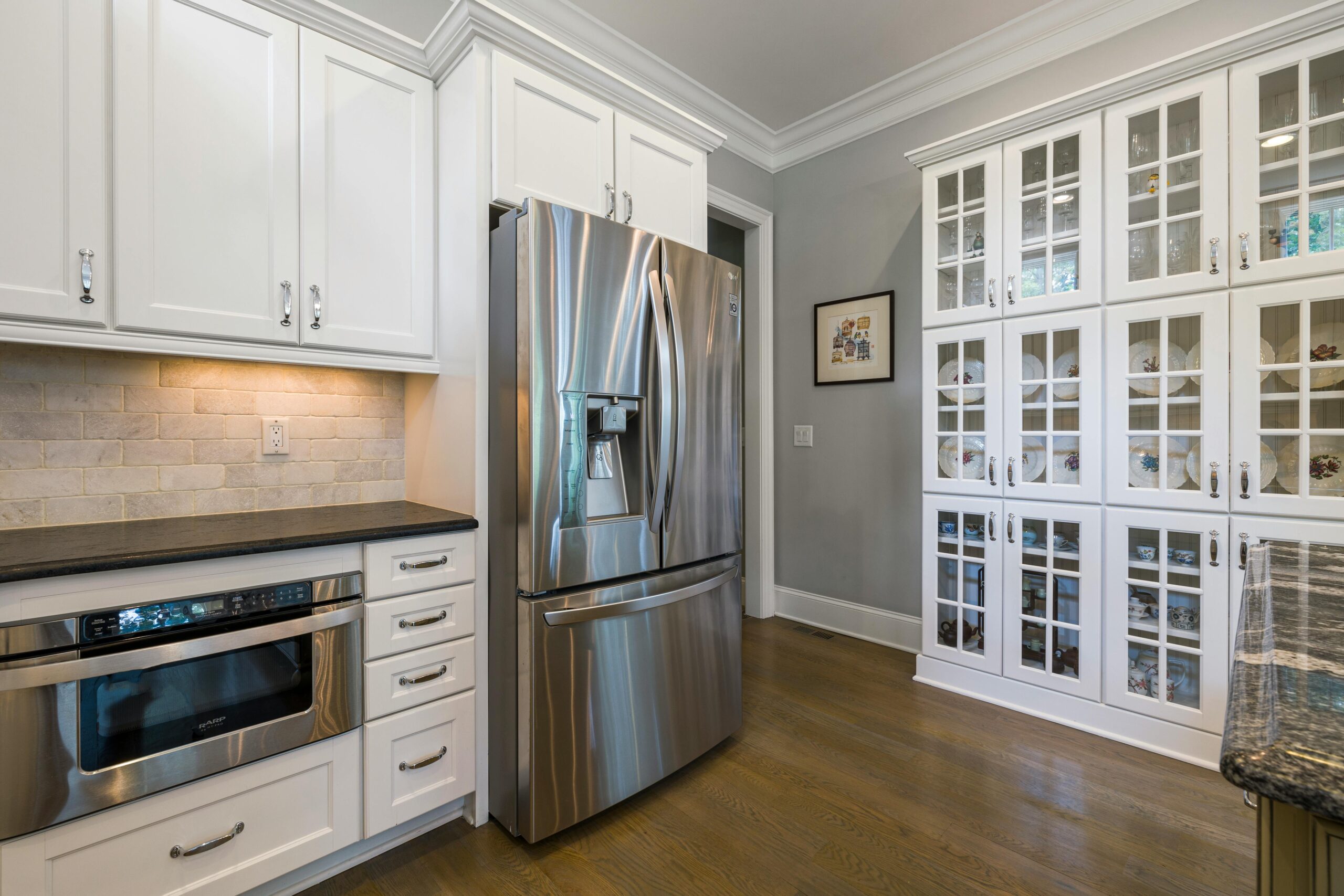 Contemporary kitchen interior featuring stainless steel fridge and white cabinets.